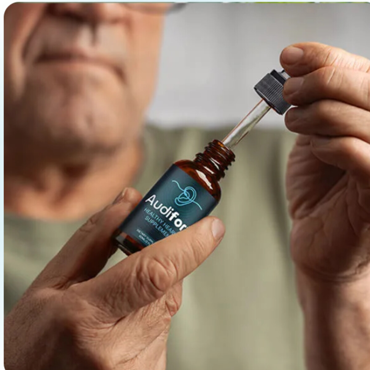 Older man using an Audifort dropper bottle